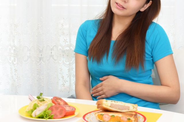 食事中に腹痛を訴える女性
